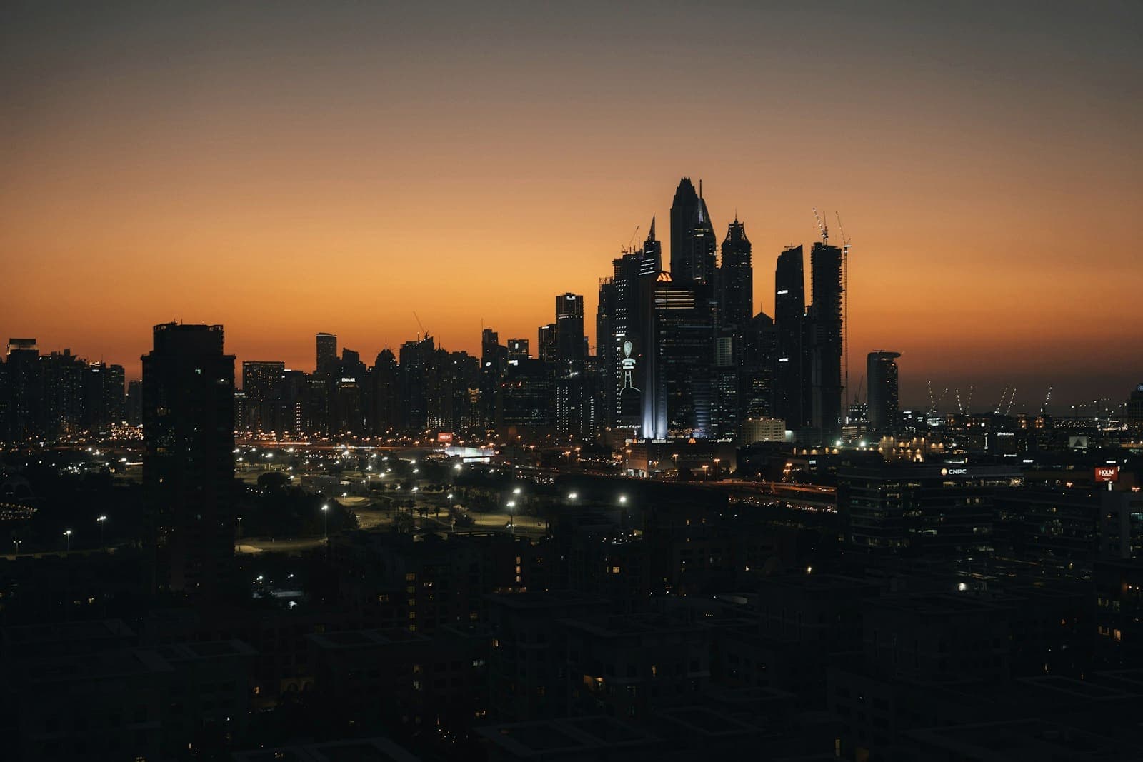 Dubai skyline silhouetted against an orange dusk sky
