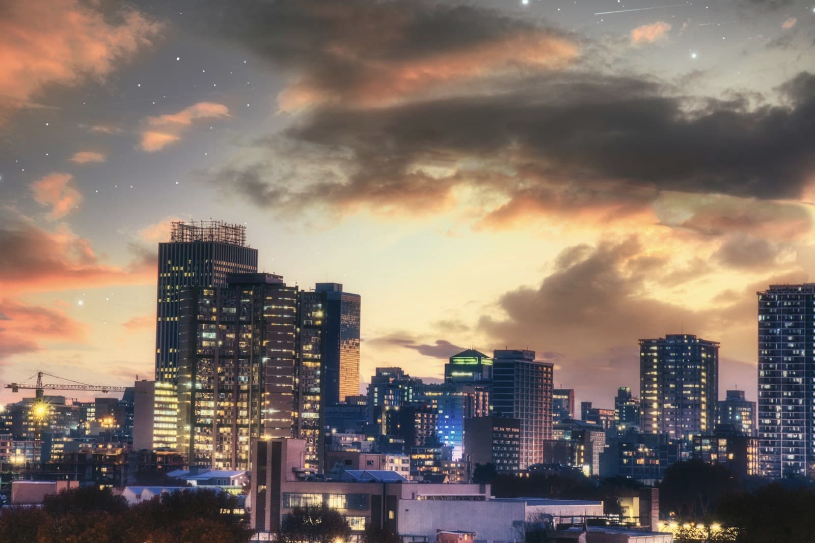 Johannesburg skyline lit up at dusk under dramatic clouds